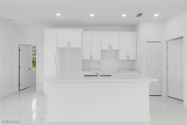 kitchen with white cabinetry, sink, and an island with sink