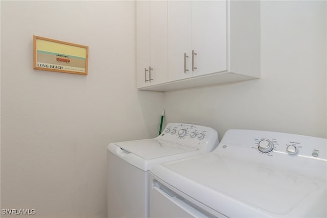 laundry room featuring separate washer and dryer and cabinets