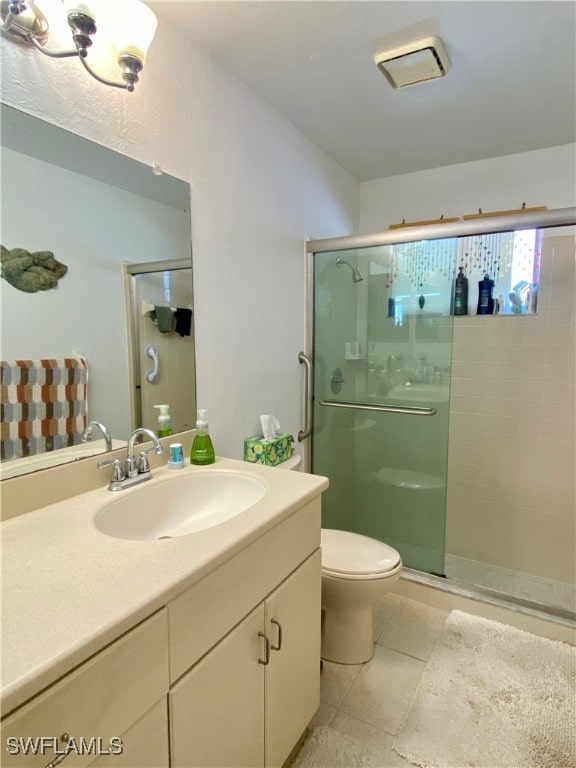 bathroom with vanity, toilet, tile patterned floors, and a shower with door