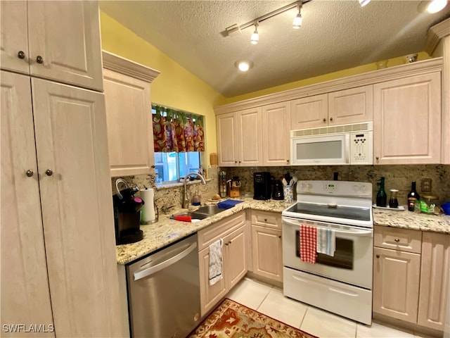 kitchen with light tile patterned floors, a textured ceiling, vaulted ceiling, sink, and white appliances