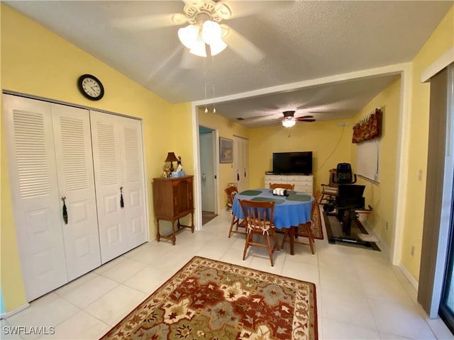 dining room featuring vaulted ceiling, a textured ceiling, light tile patterned floors, and ceiling fan