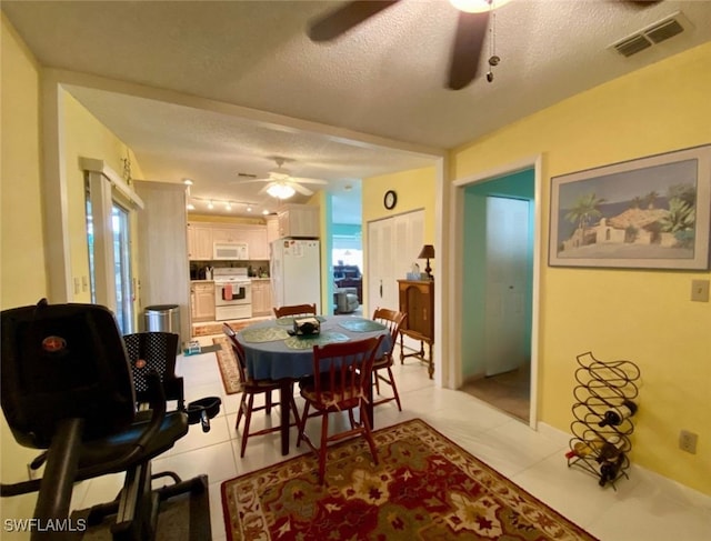 tiled dining space with a textured ceiling and ceiling fan