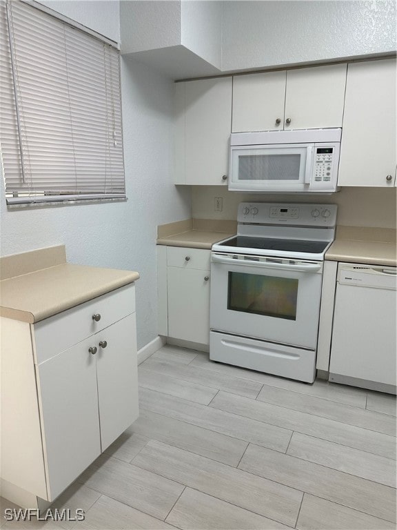 kitchen with light hardwood / wood-style floors, white cabinets, and white appliances