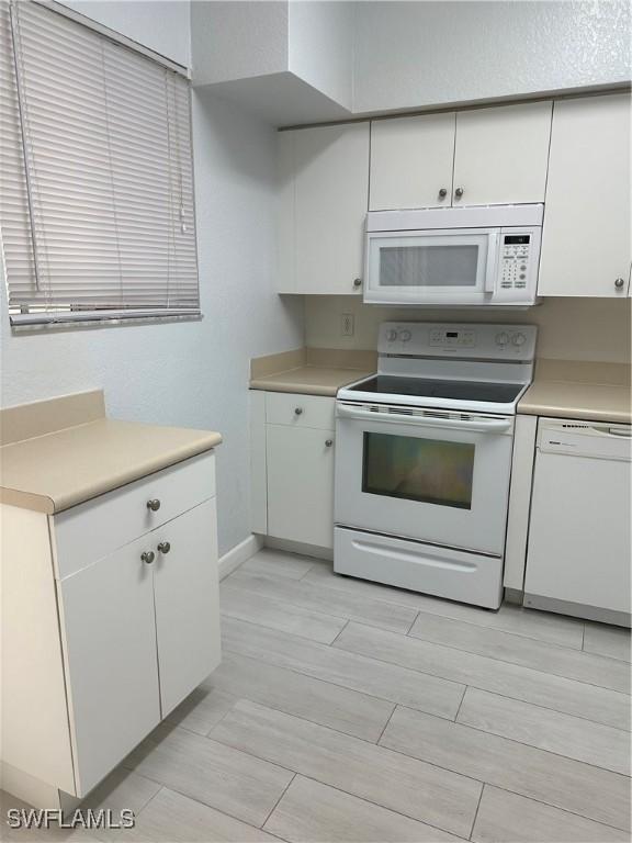 8358 Bernwood Cove Loop Unit 706, Fort Myers, FL 33966 - kitchen featuring white appliances, white cabinets, light countertops, and baseboards