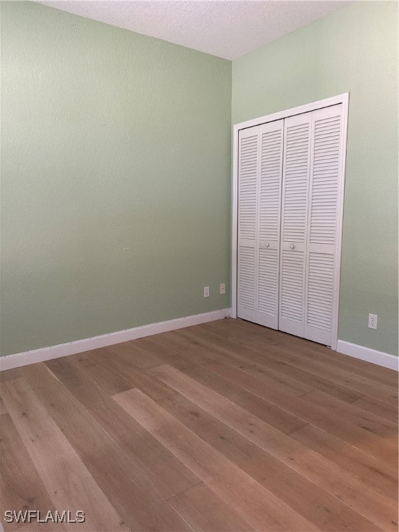 unfurnished bedroom with a closet, a textured ceiling, and hardwood / wood-style flooring