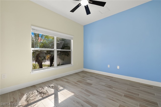 spare room featuring a ceiling fan, lofted ceiling, baseboards, and wood finished floors