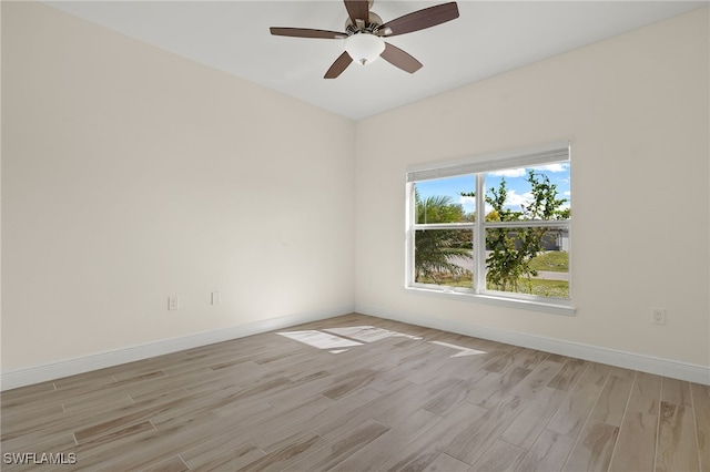 spare room featuring a ceiling fan, light wood-style flooring, and baseboards