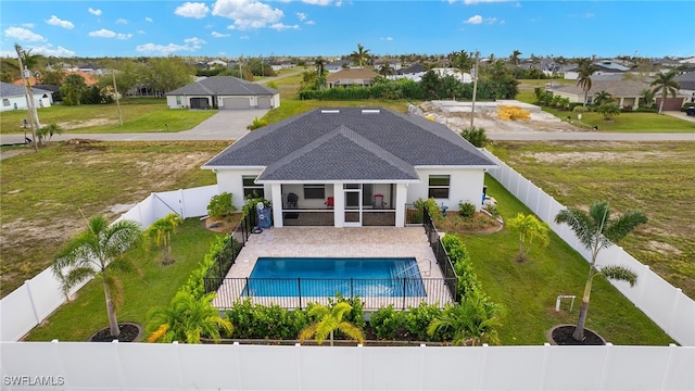 back of house featuring a sunroom, a fenced backyard, a lawn, and a fenced in pool