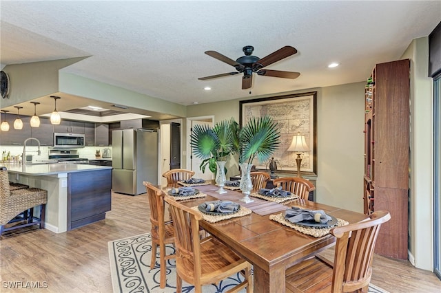 dining area with light hardwood / wood-style floors, a textured ceiling, sink, and ceiling fan