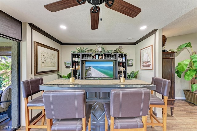 bar featuring light hardwood / wood-style floors, crown molding, a textured ceiling, and ceiling fan