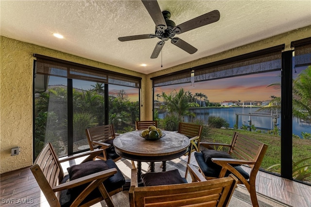 sunroom featuring a water view and ceiling fan