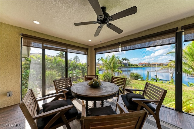 sunroom with a water view and ceiling fan