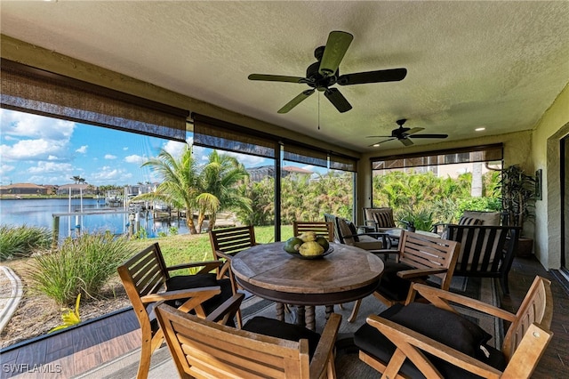 sunroom / solarium featuring a water view and ceiling fan