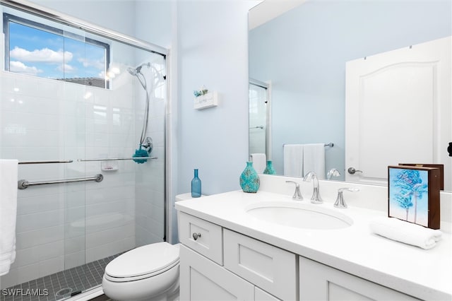 bathroom with an enclosed shower, vanity, and toilet