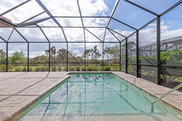 view of swimming pool featuring glass enclosure and a patio