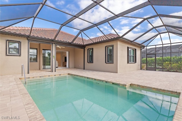 view of swimming pool with glass enclosure, ceiling fan, and a patio