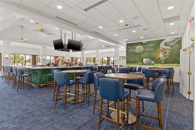 interior space featuring ceiling fan, dark carpet, and indoor bar