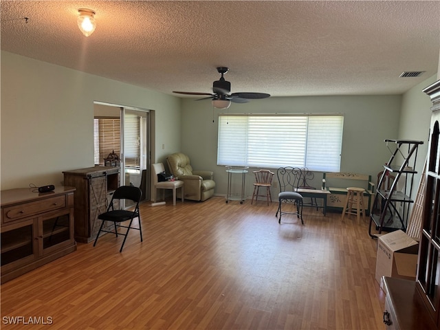 sitting room with ceiling fan, a textured ceiling, and hardwood / wood-style flooring