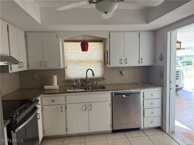 kitchen with sink, stainless steel appliances, a raised ceiling, backsplash, and dark stone countertops