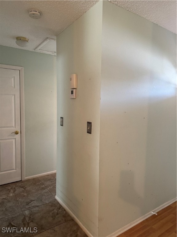 hall featuring dark wood-type flooring and a textured ceiling