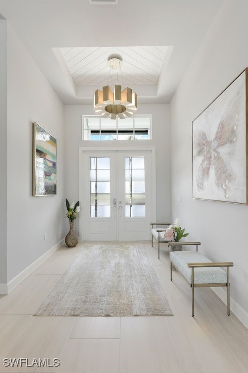 tiled foyer entrance with wood ceiling, a raised ceiling, and an inviting chandelier