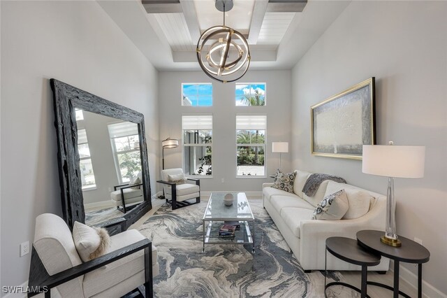 living room with a towering ceiling, a notable chandelier, and a raised ceiling