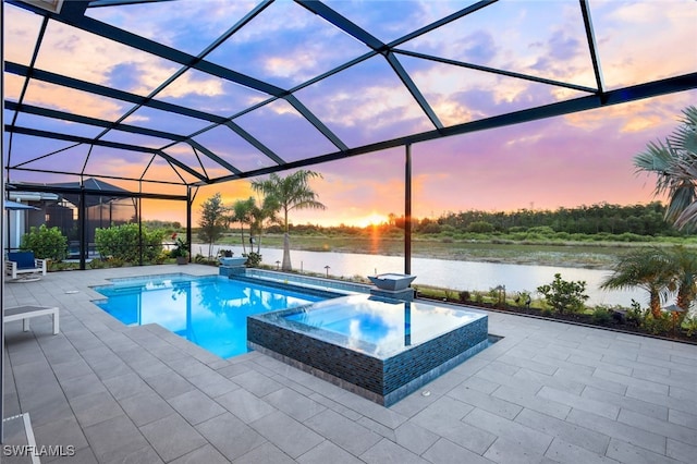 pool at dusk with a lanai, an in ground hot tub, a water view, and a patio area