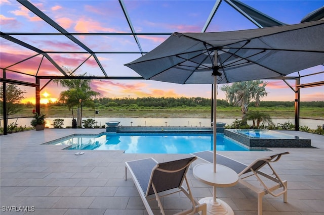 pool at dusk featuring a lanai, a water view, a patio, and an in ground hot tub