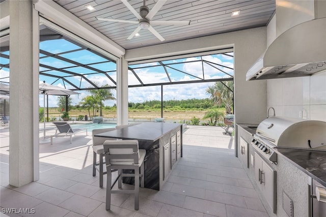 view of patio featuring glass enclosure, exterior kitchen, and area for grilling