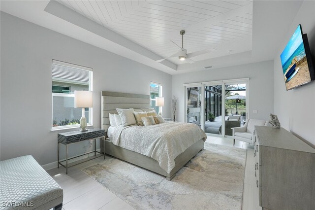 bedroom featuring a tray ceiling, multiple windows, ceiling fan, and access to exterior