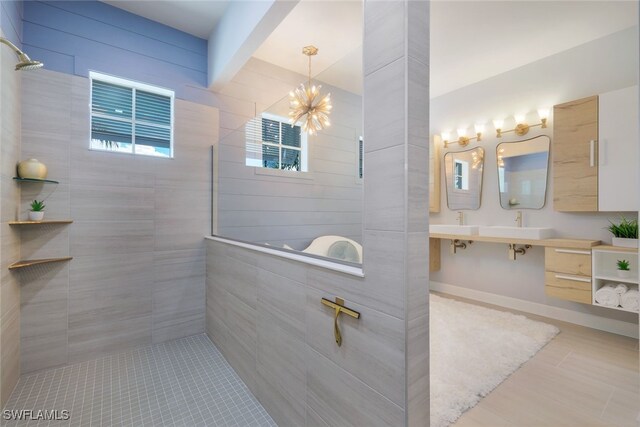 bathroom with vanity, an inviting chandelier, tile patterned floors, and tiled shower