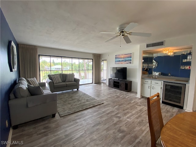 living room featuring ceiling fan, bar area, hardwood / wood-style floors, and beverage cooler