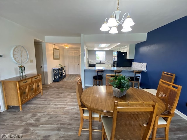 dining room featuring a notable chandelier, hardwood / wood-style floors, and a skylight