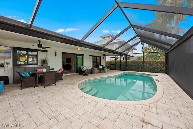 view of swimming pool with a patio area, ceiling fan, and glass enclosure