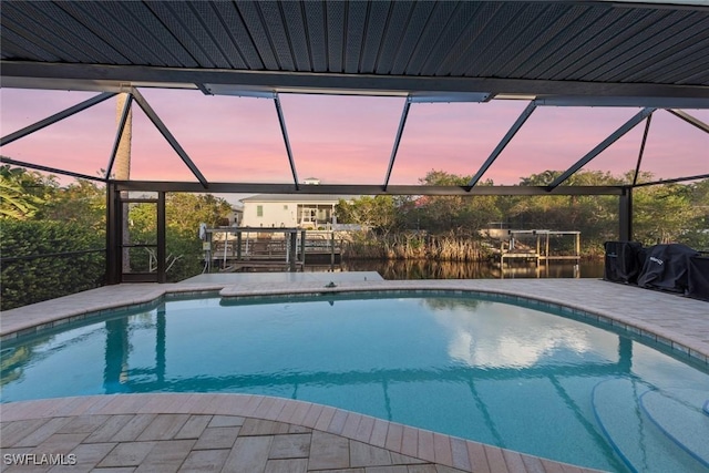 pool at dusk with glass enclosure and a patio