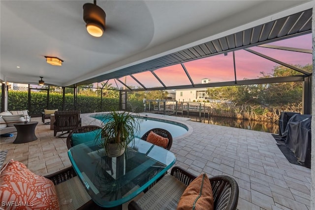 patio terrace at dusk featuring area for grilling, an outdoor living space, and a lanai