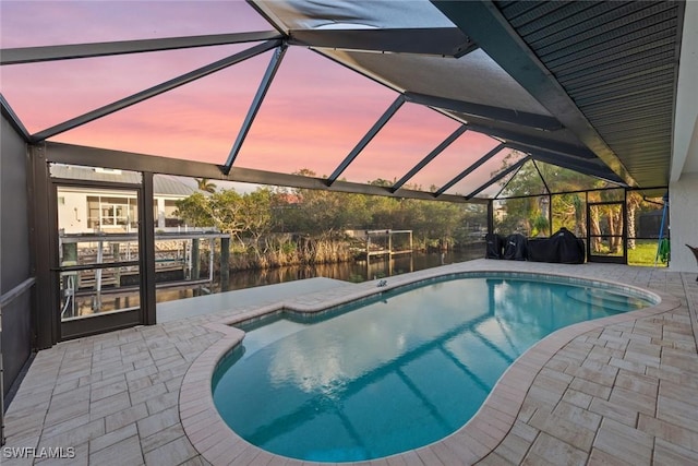 pool at dusk featuring a lanai and a patio area