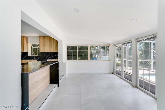 kitchen with vaulted ceiling, decorative backsplash, light tile patterned floors, and light brown cabinets