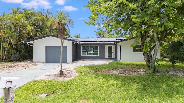 ranch-style house with a garage, a front lawn, and solar panels