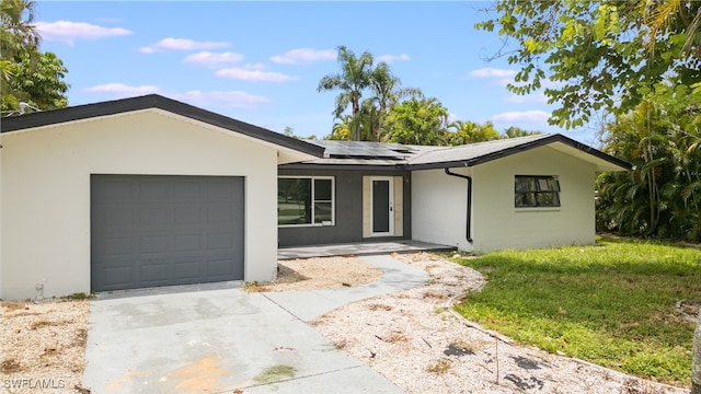 ranch-style home with a garage and solar panels