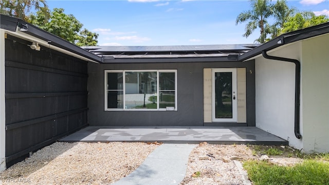 entrance to property with solar panels and a patio area