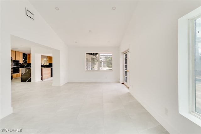 tiled spare room featuring vaulted ceiling