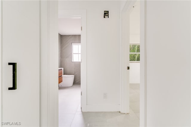 hallway with light tile patterned flooring and tile walls