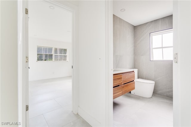 bathroom with vanity, toilet, tile patterned floors, and tile walls