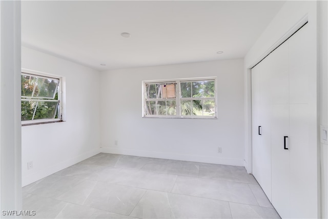 unfurnished bedroom featuring multiple windows, a closet, and light tile patterned floors