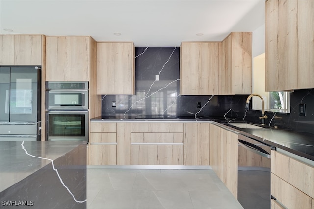 kitchen featuring tasteful backsplash, appliances with stainless steel finishes, sink, light tile patterned floors, and light brown cabinets