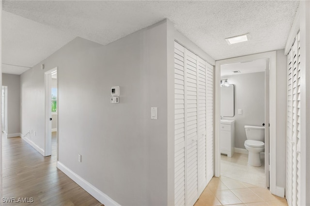 hallway featuring light wood-type flooring and a textured ceiling