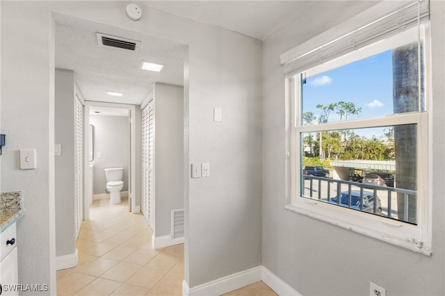 1660 Pine Valley Dr Unit 203, Fort Myers, FL 33907 - hallway featuring light tile patterned floors, a textured ceiling, and baseboards