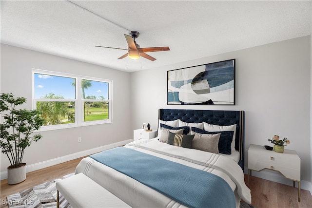 bedroom with hardwood / wood-style floors, ceiling fan, and a textured ceiling