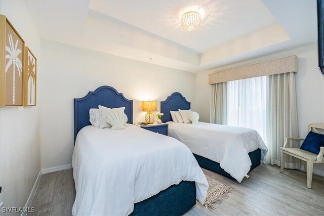 bedroom with hardwood / wood-style flooring and a raised ceiling